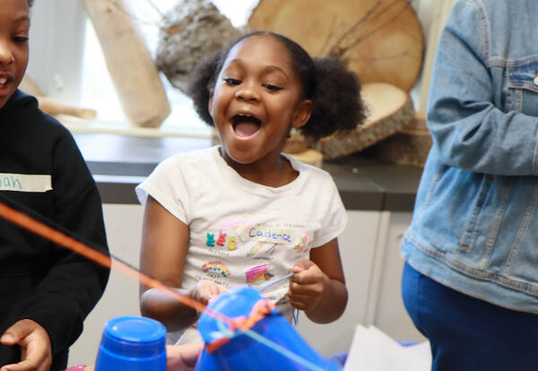 A smiling student holds a string attached to a cup