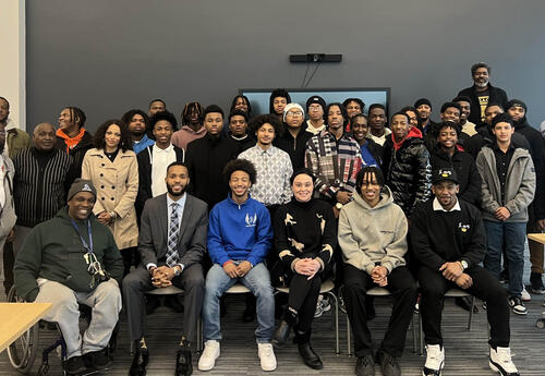 Group photo of students and summit speakers in the library