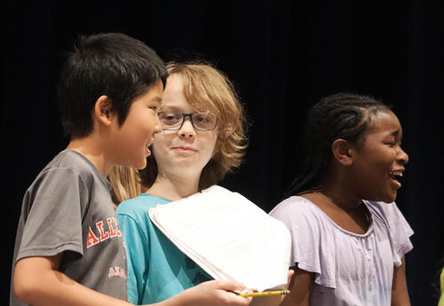 Three student actors rehearse their lines onstage