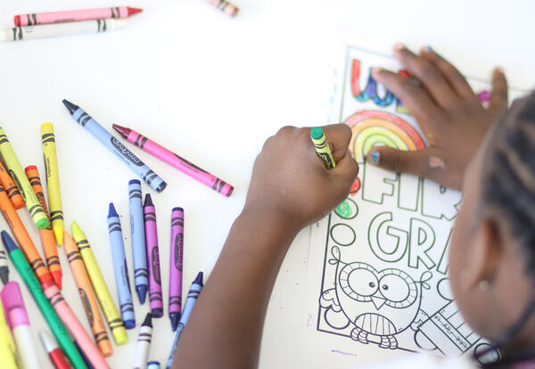 Overhead view of a student drawing with crayons