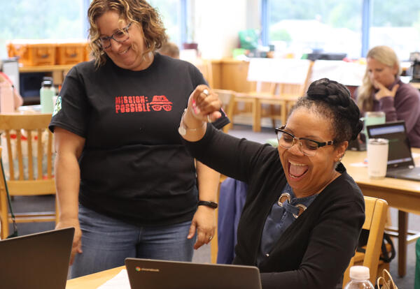 Teacher at laptop is jubilant when she solves a tech problem