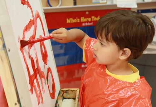 Student dabs red paint on white paper