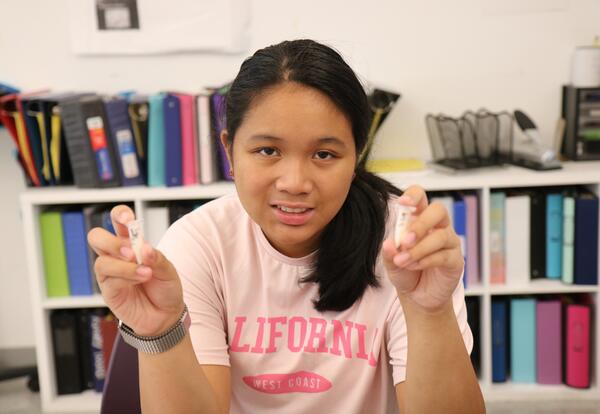A student holds up chocolate milk samples that she separated using a centrifuge.