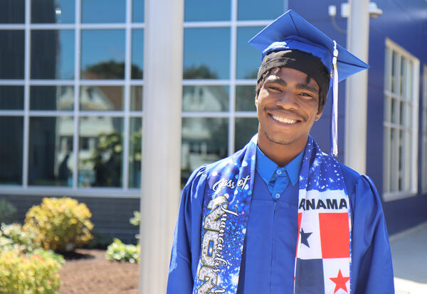 Photo of graduate in cap and gown outside of Albany High school