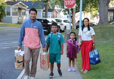 A family carries school supplies into school on the first day.