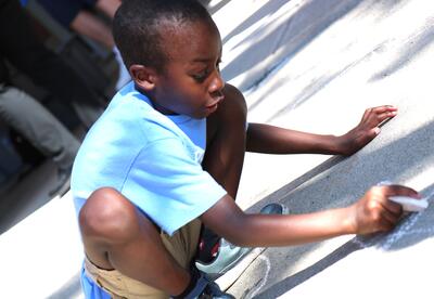 A student decorates the sidewalk in advance of the first day of school.
