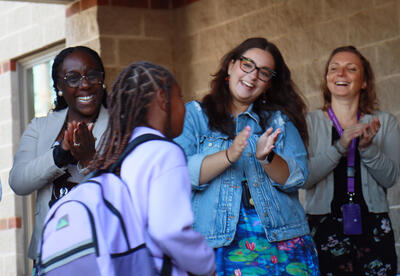 Teachers applaud student as they enter school