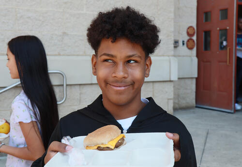 Student holds up a tray with a hamburger on it