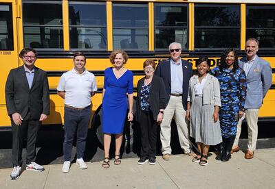Superintendent Hochreiter and board members join city and transportation leaders in front of a yellow school bus