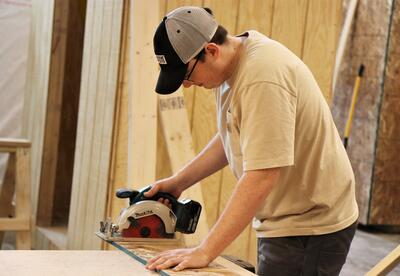 Construction technology student using a power tool to cut wood