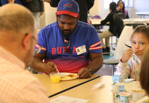 A dad and his daughter eat breakfast together.