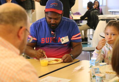 A dad and his daughter eat breakfast together.