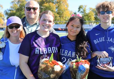 Photo of two seniors from the girls' soccer team from last year posing with loved ones.
