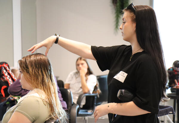 Mendrick demonstrating a blow dry technique to students