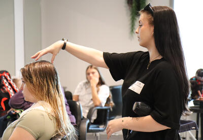 Mendrick demonstrating a blow dry technique to students