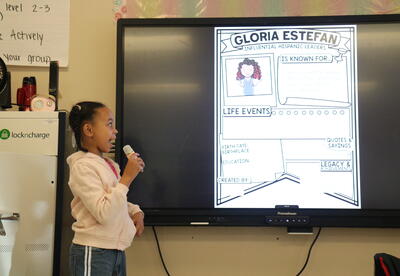 A student leads a presentation on Gloria Estefan.