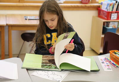 A third grader reads a book about Jane Goodall.