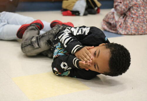 A student practices stop-drop-roll with help from the fire department.