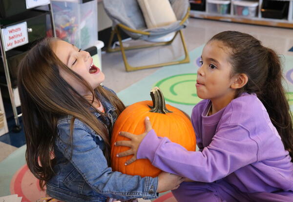 Two students work together to weigh a pumpkin.