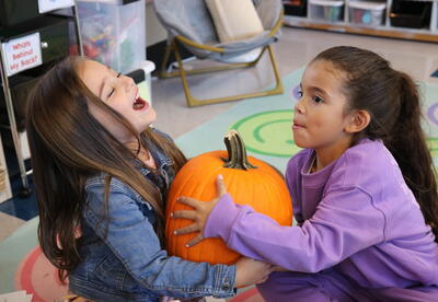 Two students work together to weigh a pumpkin.