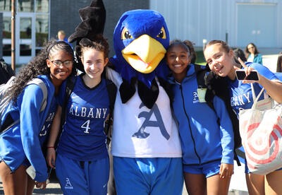 Students posing with the Falcon mascot during the Homecoming Parade