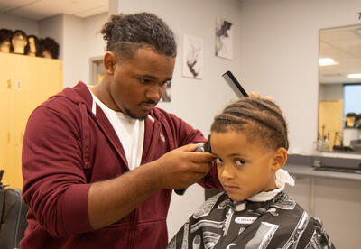 Barbering student trims the sides of elementary student's hair