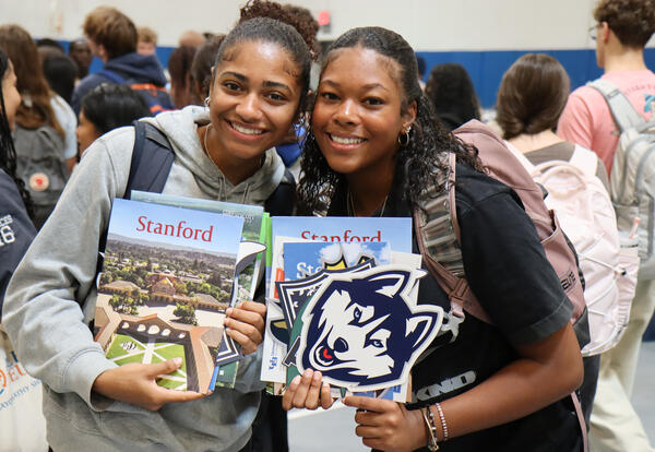 Two students at college fair event with college brochures