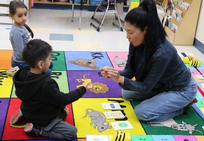 A tech coach teaches students how to program bug robots.