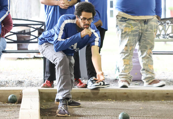 Albany High student-athlete throwing a bocce ball as teammates look on