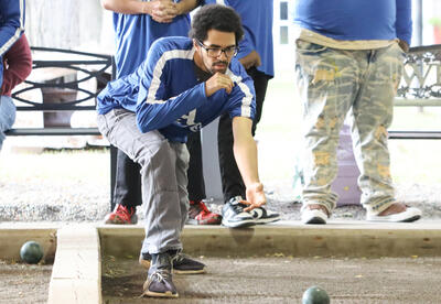 Albany High student-athlete throwing a bocce ball as teammates look on