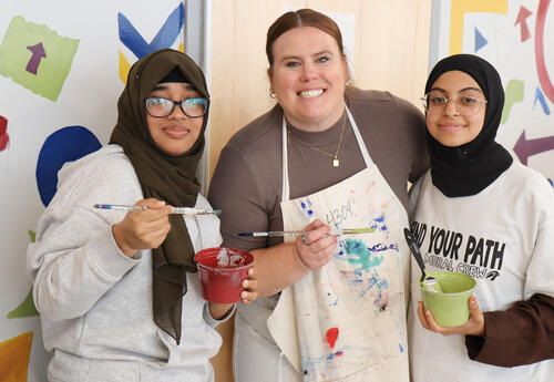 鶹ӰԺ High teacher working on the mural with two students