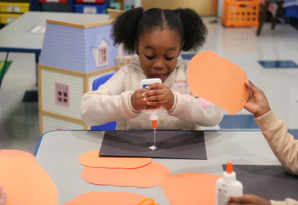 A student completes a pumpkin craft.