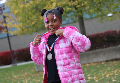 A student poses with her medal after a running race.