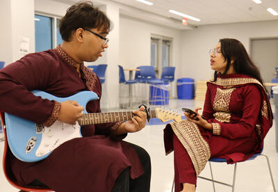 Photo of two students wearing traditional dress performing a song together