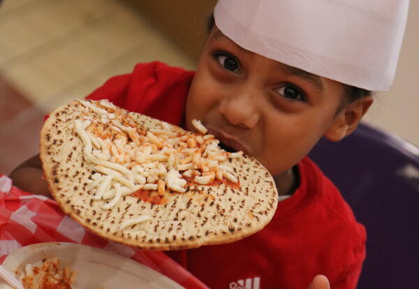 A student smiles while eating a pizza he ate.