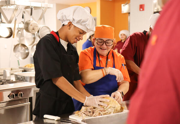 Student and Chef Valentine carving a turkey