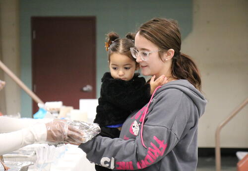 A mother and daughter take a plate of turkey and fixins' at a holiday party.