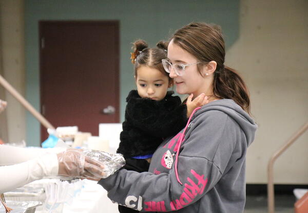 A mother and daughter take a plate of turkey and fixins' at a holiday party.