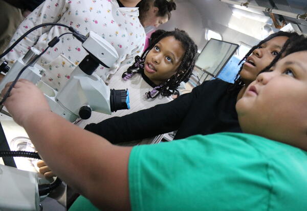 Students practice using a  microscope.