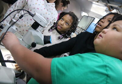 Students practice using a  microscope.