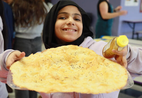 Student shows off the homemade Lebanese pastry she brought to the feast