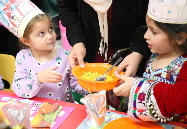 Two students pass a bowl of corn during a Thanksgiving party.