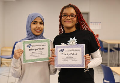 Two students holding their honor roll certificates
