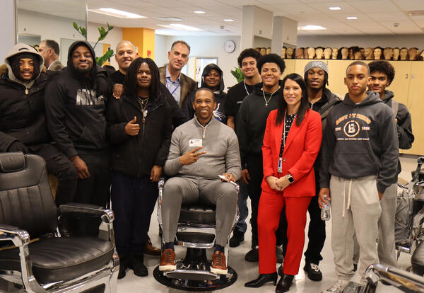 Secretary of State Mosley showing off his new haircut, surrounded by Albany High barbering students