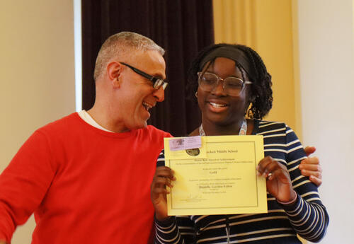 Principal hugs smiling honor roll student