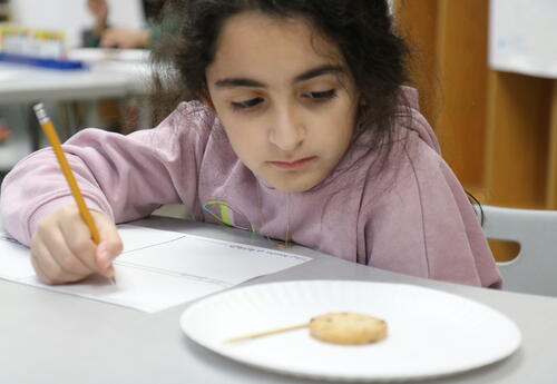 A student learns about archaeology by excavating a cookie.