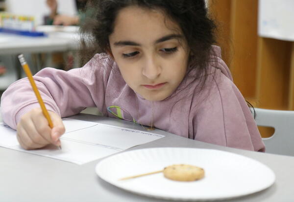 A student learns about archaeology by excavating a cookie.