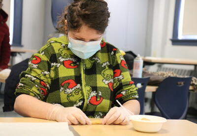 A student rolls out dough to make cookies.