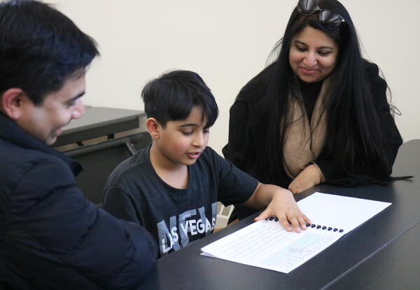 A student shares his writing journal with his parents.