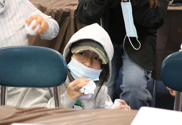 A student crouches behind a desk during a trench battle simulation.